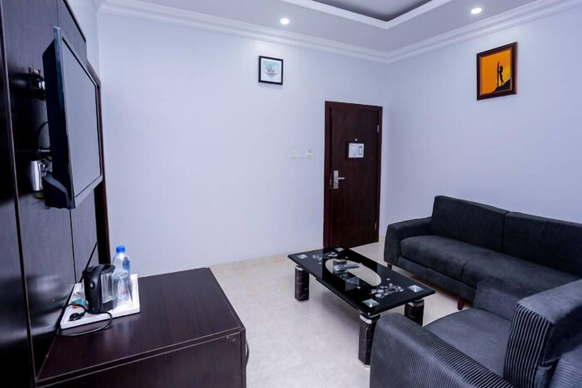 A modern living room with a dark sofa, a coffee table, and a flat-screen TV.