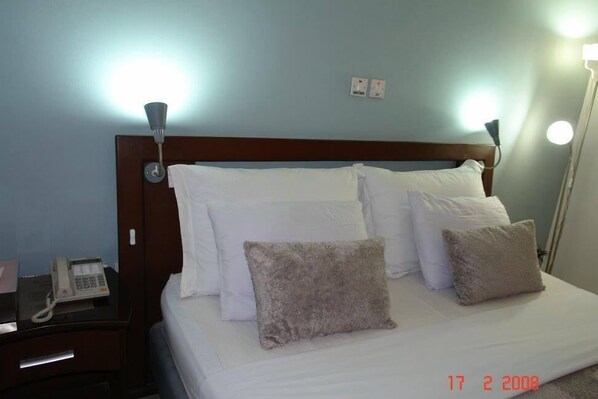 Une chambre d’hôtel comprenant un lit, deux lampes de chevet, une table de chevet avec un téléphone et une prise électrique au mur.