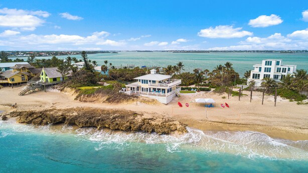 A coastal property with a large house, a beach, and a rocky shoreline.