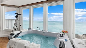 A hot tub with a view of the ocean, a telescope, and towels.