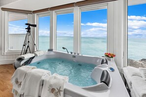A hot tub with a view of the ocean, a telescope, and towels.