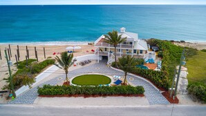A beachfront property with a pool, lounge chairs, and a view of the ocean.