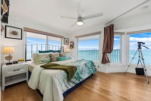 Een slaapkamer met een groot bed, een plafondventilator en uitzicht op de oceaan.