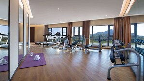 Un gimnasio espacioso con equipo de ejercicio, ventanas amplias y vistas a las montañas.