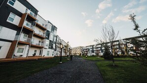 En moderne boligbygning med flere altaner, en grussti og en græsplæne.