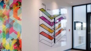 Et moderne interiør med farverig geometrisk vægkunst og et tydeligt, nummereret gulvplan på væggen.