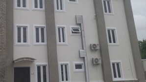A multi-story building with a beige facade, white-framed windows, and an air conditioning unit on the exterior wall. - Marshall Hotel Apartments (Kano)