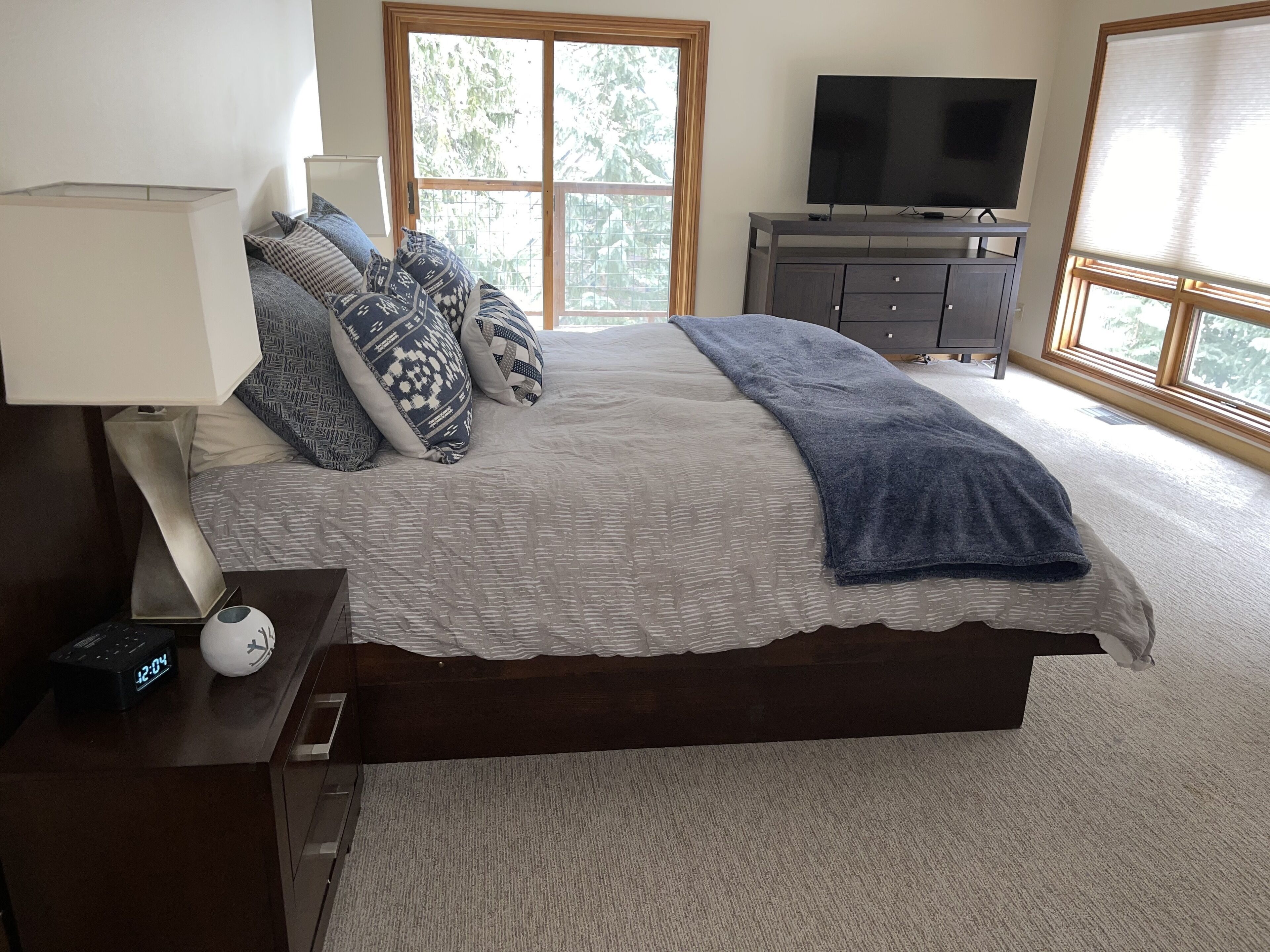 A bedroom with a bed, a TV, a dresser, and a window.