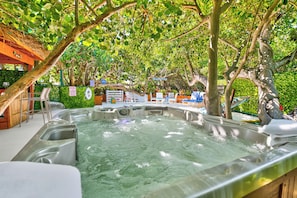A hot tub area with multiple tubs, surrounded by trees and a wooden structure. - Bathtub Beach Retreat: 8BR/4BA Ocean-to-River w/heated pool +Elevator Discounts! (Stuart)