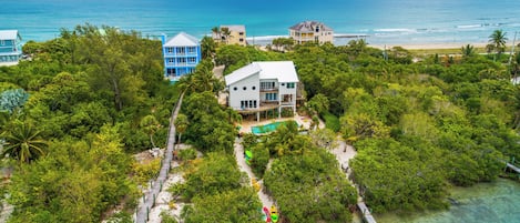 A coastal property with a white house, a blue building, and a beach view.