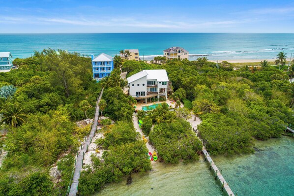 A coastal property with a white house, a blue building, and a beach view.