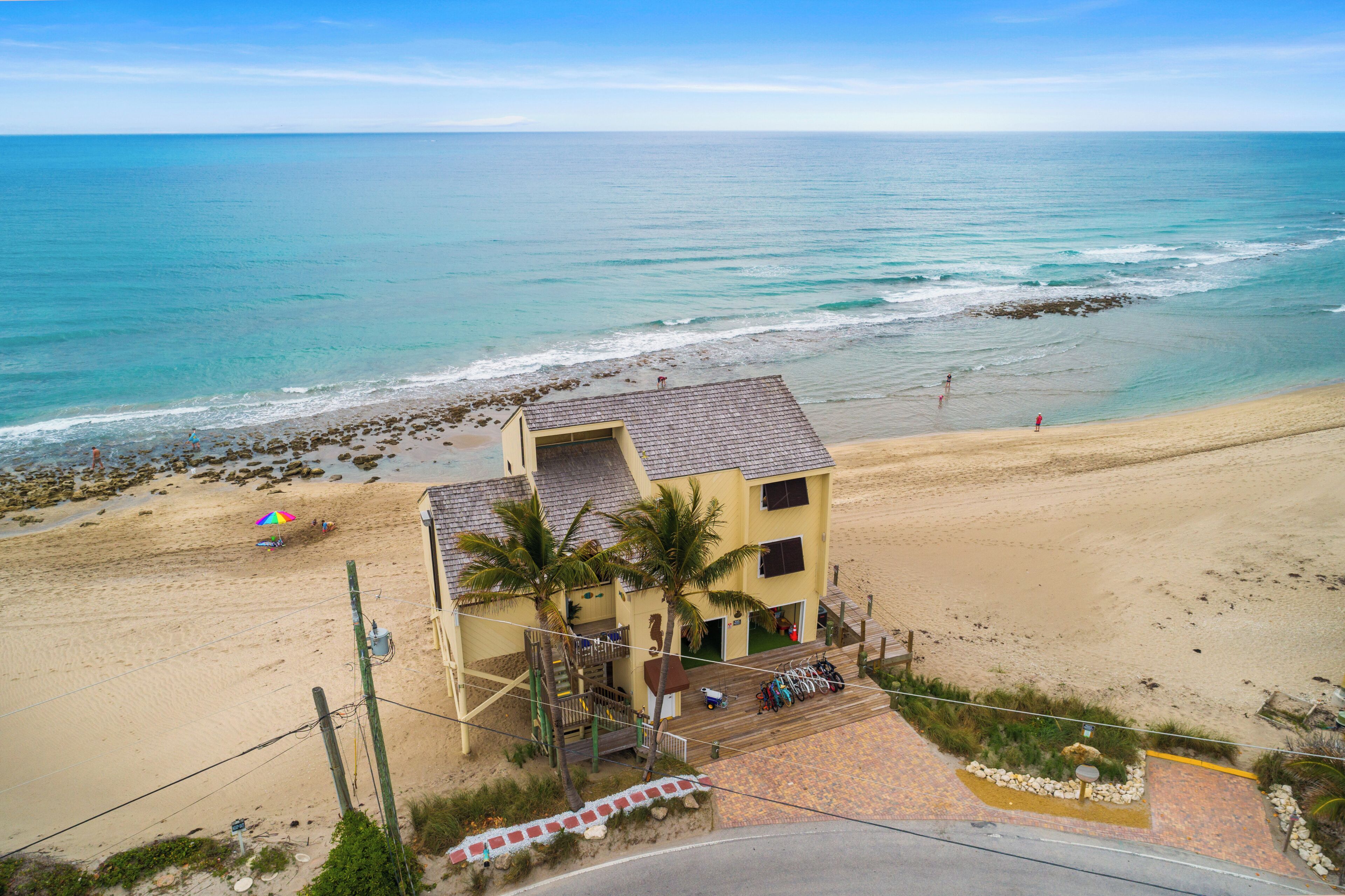 Una propiedad frente al mar con un edificio de dos pisos, un sendero pavimentado y vista al océano.