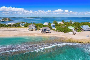 A coastal property with a beach, clear waters, and a view of the sea.