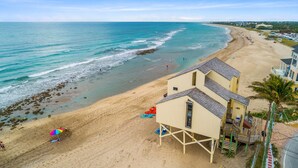 A beach with a lifeguard tower, beach umbrellas, and a sandy shoreline.