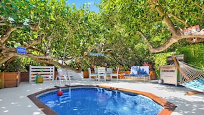 A swimming pool surrounded by trees and outdoor furniture.