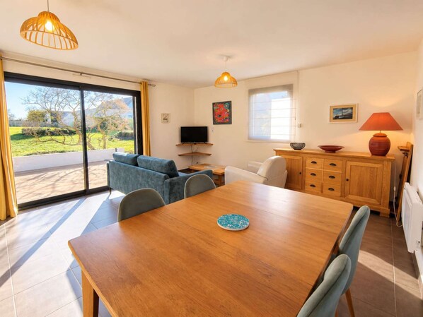 A modern living room with a sofa, a dining table, and a kitchen area with cabinets and a TV.