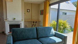 Una sala de estar moderna con sofá, chimenea y un amplio ventanal corredera a un balcón.