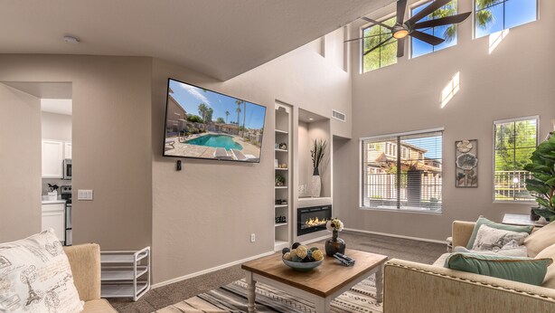 A spacious living room with a flat-screen TV, comfortable seating, a fireplace, and large windows. - Group Luxury Retreat ~ 4 Neighboring Homes, 21 Beds, Pool & Golf Community (Mesa)