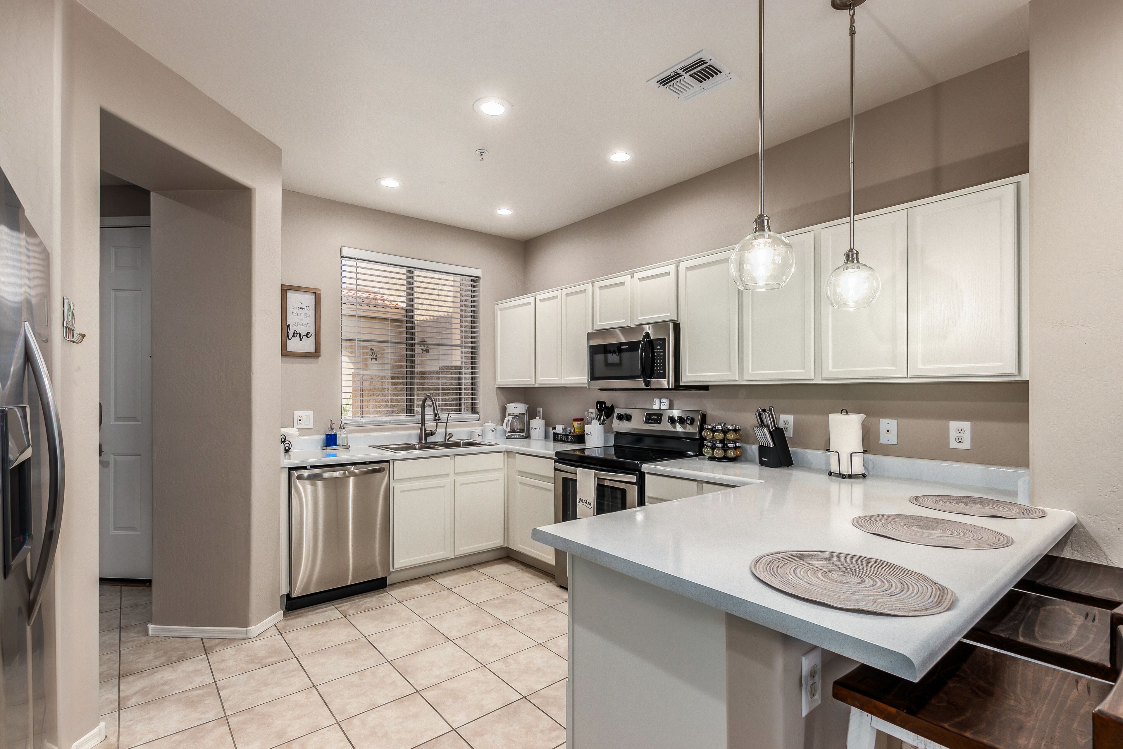 A modern kitchen with white cabinets, stainless steel appliances, and a central island with a light-colored countertop.