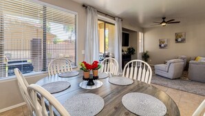 A dining area with a round table, white chairs, and woven placemats. - Group Luxury Retreat ~ 4 Neighboring Homes, 21 Beds, Pool & Golf Community (Mesa)