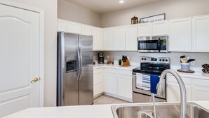 A modern kitchen with white cabinets, stainless steel appliances, and a built-in oven. - Group Luxury Retreat ~ 4 Neighboring Homes, 21 Beds, Pool & Golf Community (Mesa)