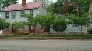 A two-story house with a red roof, green trim, and a brick foundation. - Cobbler Suite, Private Entrance and Private bath, 100% NO SMOKING PROPERTY! (Hermann)
