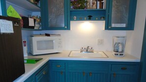 A kitchen with teal cabinets, a white microwave, a coffee maker, and a sink. - Cobbler Suite, Private Entrance and Private bath, 100% NO SMOKING PROPERTY! (Hermann)