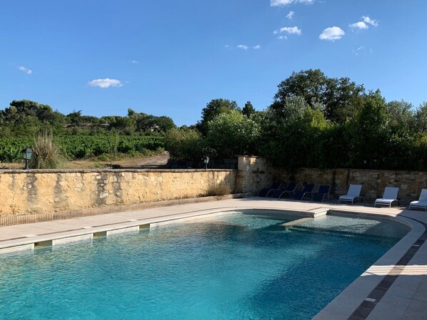 A swimming pool with lounge chairs and a stone wall.