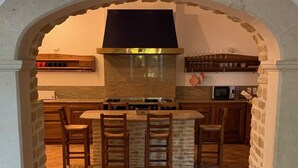 Une cuisine avec une arche en pierre, un îlot central doté de tabourets, une cuisinière et un four à micro-ondes.