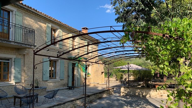 Un bâtiment en pierre doté d’un patio couvert, d’un espace extérieur aménagé pour s’asseoir et d’une pergola.
