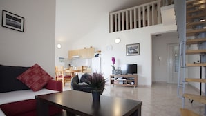 A modern living room with a sofa, a coffee table, and a TV stand. There is a staircase leading to an upper level. - Apartment Nina - Large 2 bedroom Apt  250m Beach amenities 100m Free Parking (Split)