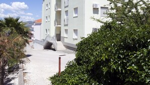 Ein mehrstöckiges Gebäude mit Balkonen, einem Kiesweg und umgebender Bepflanzung.