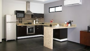 A modern kitchen with a central island, built-in microwave, oven, and stainless steel range hood. - Sole Suites Playa del Carmen (Playa del Carmen)