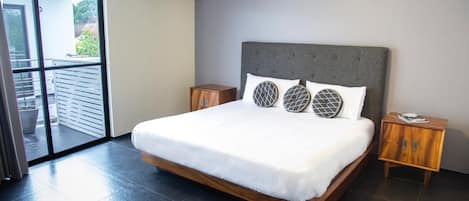 A modern bedroom with a large bed, two wooden nightstands, and a balcony with a sliding door.