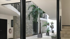 A spacious indoor area with a modern design, featuring a staircase, a fire extinguisher, and potted plants. - Sole Suites Playa del Carmen (Playa del Carmen)