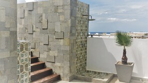 A staircase leading to a balcony with a view of the sea, a palm tree, and a patterned wall. - Sole Suites Playa del Carmen (Playa del Carmen)
