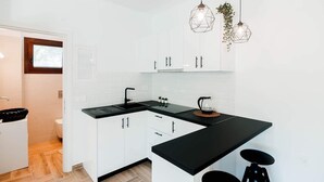 Een moderne keuken met witte kasten, een zwart aanrecht en hanglampen.
