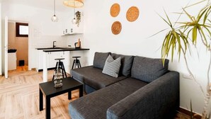 Een moderne woonkamer met een grijze bank, een salontafel en een hanglamp.