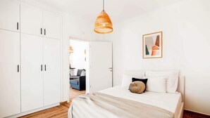 Een slaapkamer met een bed, een witte kledingkast en een hanglamp.
