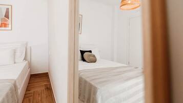 Habitación de hotel con dos camas, suelo de madera y una lámpara colgante anaranjada.
