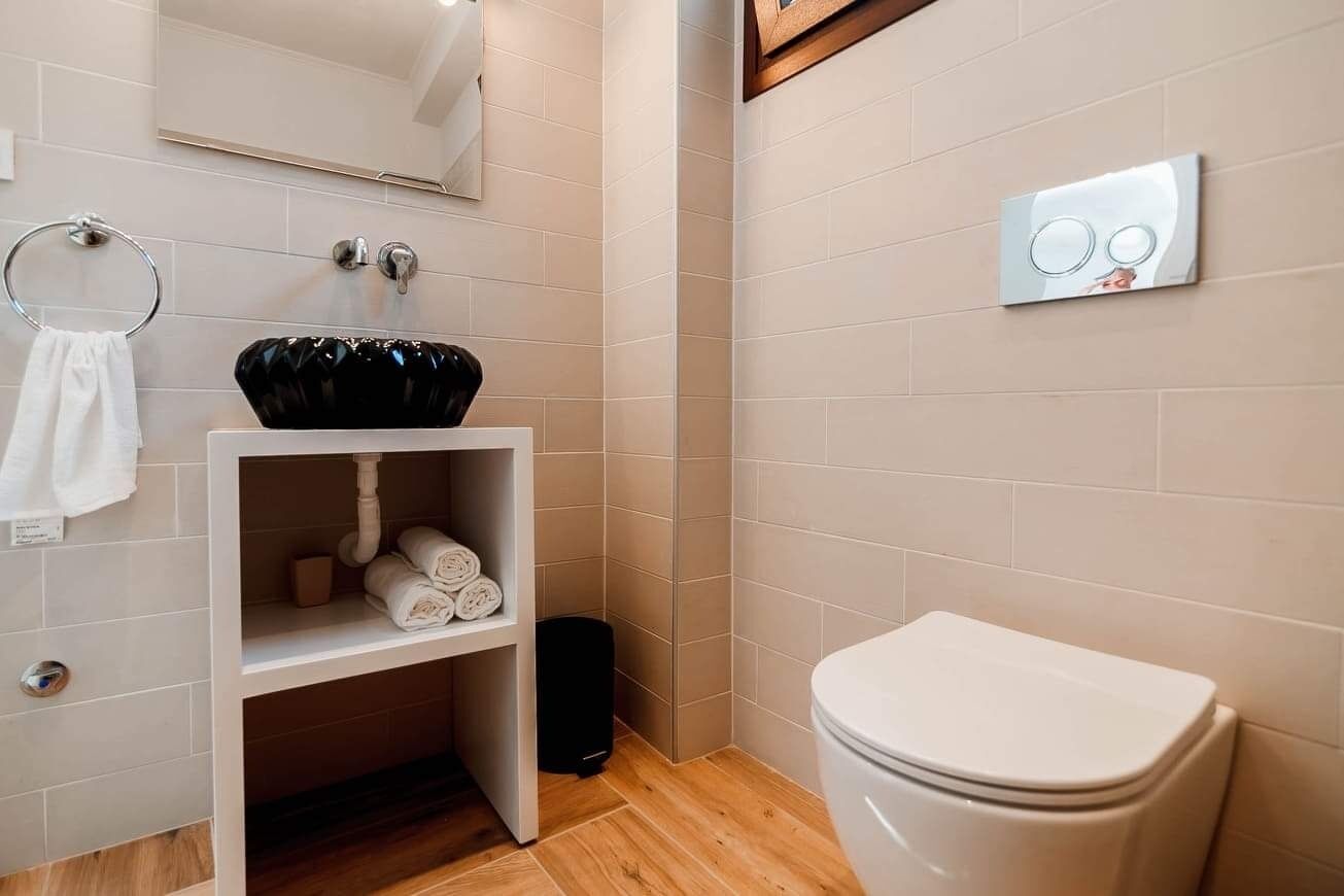 Ein modernes Badezimmer mit einem weißen Waschbecken, einer Toilette und einem Handtuchhalter.