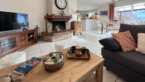 Una sala de estar con chimenea, televisor, sofá y comedor con vistas.