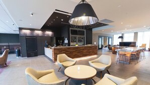 A modern hotel lobby with a bar area, seating arrangements, and a large TV screen. - Courtyard by Marriott Cartersville (Cartersville)