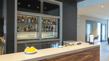Eine Bar mit Regalen voller Spirituosenflaschen und Gläsern, einer Zitronenschale und einem Menüständer.