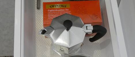 A drawer containing a coffee maker, tea bags, a spoon, and a box of Twinings English Breakfast Tea.