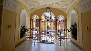Un interior con pared amarilla, suelo de mármol y techo decorativo.