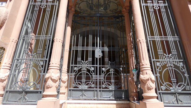 Fachada de edificio con puertas de hierro forjado ornamentadas y columnas.