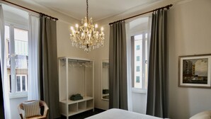 Un dormitorio con una cama grande, un armario, una silla, una araña y un cuadro en la pared.
