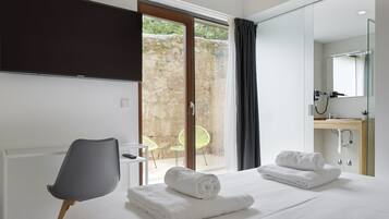 Quarto de hotel com cama, cadeira, televisão, banheiro e vista para o exterior.