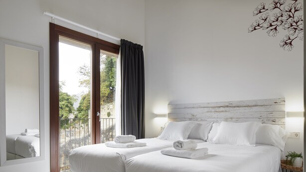 A bedroom with a large bed, a balcony, and a view of trees.